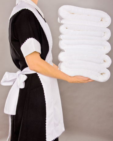 Maid holding white stack towels